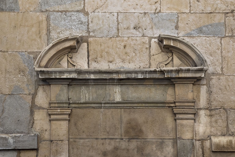 Premier logis secondaire, façade antérieure : détail du fronton interrompu de la porte murée.